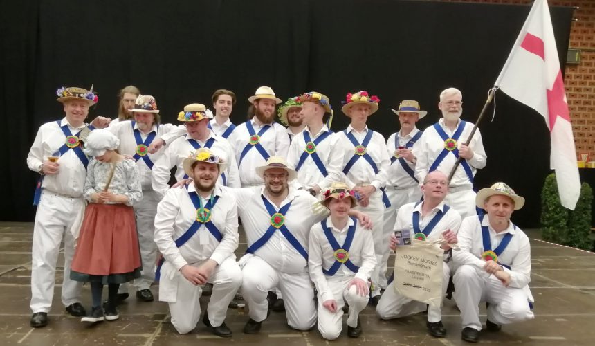 Jockey Morris are posing together for a team photo. They wear white shirts with blue baldrics.